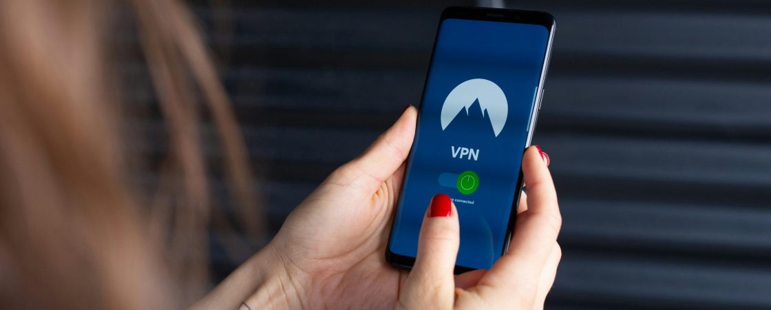 Close-up of a woman's hands using a VPN app on a smartphone, emphasizing digital security.